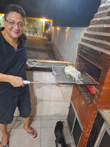 a man is cooking a bird on a grill at Pousada Hotel Araguaia in Aragarças