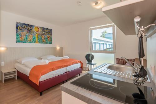 Schlafzimmer mit einem Bett, einem Waschbecken und einem Schreibtisch in der Unterkunft FairSleep Motel Einstein Erding in Erding