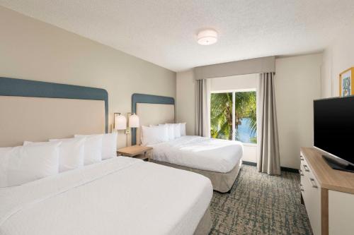 a hotel room with two beds and a flat screen tv at Homewood Suites Miami Airport/Blue Lagoon in Miami