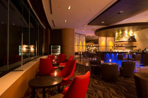 a restaurant with red chairs and tables and a bar at Hilton Tokyo Narita Airport in Narita
