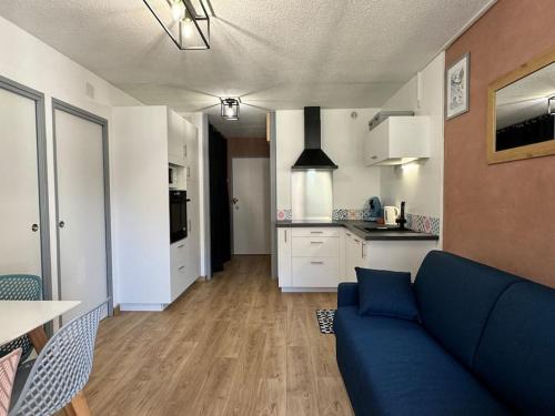 un salon avec un canapé bleu et une cuisine dans l'établissement Joli 3 pièces 40m2. 2 chambres., à Cauterets
