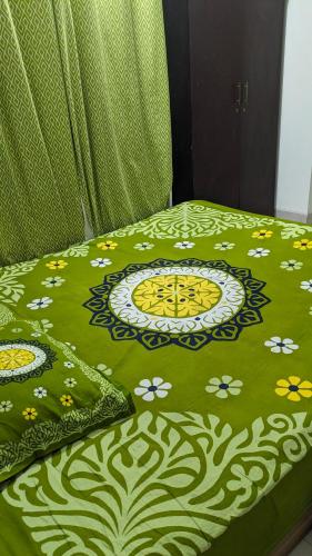 a bed with a green comforter with flowers on it at Sheikh Manama Tower in Dhaka