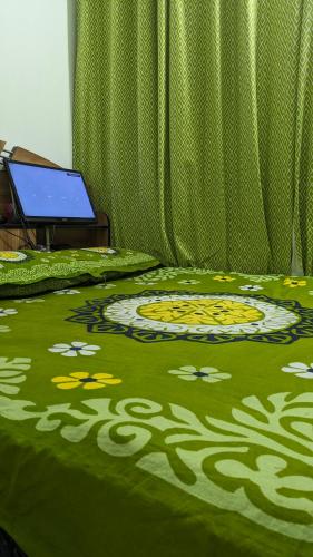 a bed with a green blanket with flowers on it at Sheikh Manama Tower in Dhaka