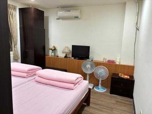 1 Schlafzimmer mit 2 Betten mit rosa Kissen und einem Ventilator in der Unterkunft 今友緣二館民宿 in Dongyin/