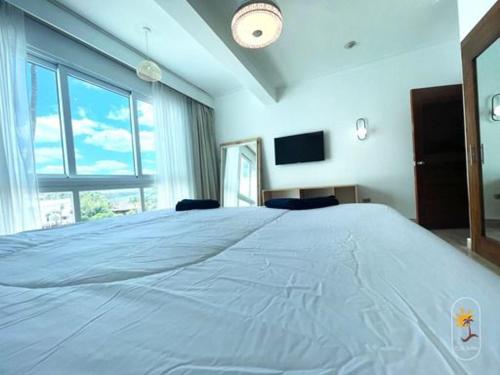 a large bed in a room with a large window at Suites Presidencial Boca chica in Cuevas