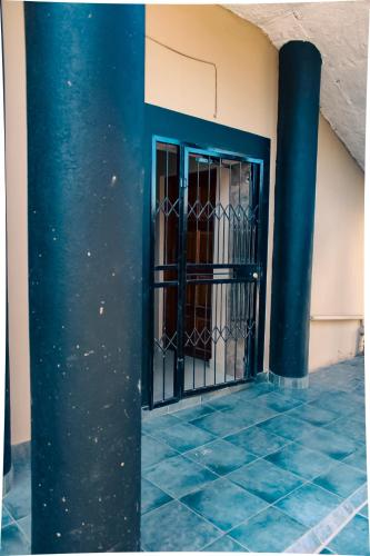 a blue iron gate in a building with a pillar at City Centre Apartment in Mbabane