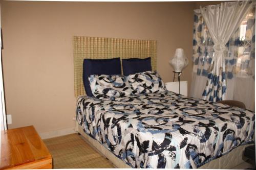 a bedroom with a bed with a black and white comforter at City Centre Apartment in Mbabane