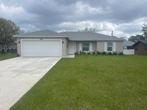 a house with a garage and a green lawn at Modern and comfortable new home with hot tub in Fort Pierce