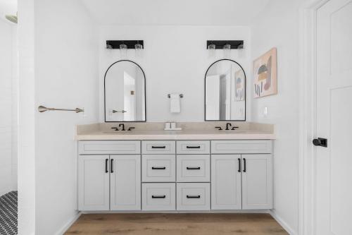 a white bathroom with two sinks and two mirrors at Las Luces in Spicewood
