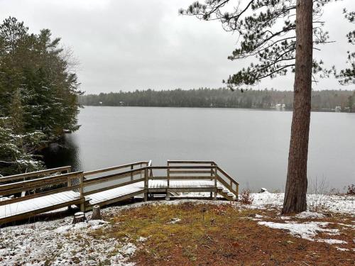 eine Bank neben einem See mit Schnee auf dem Boden in der Unterkunft KerryAnne - North Kawartha Lakehouse with Hot Tub in woodview