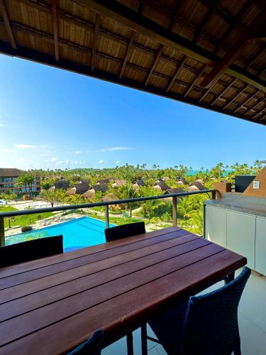 - une table en bois sur un balcon avec vue sur la piscine dans l'établissement Flat Eco Resort Praia Dos Carneiros, à Praia dos Carneiros