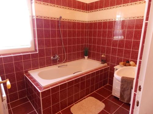 a red tiled bathroom with a tub and a sink at Éden Villa Apartmanház in Balatonfüred