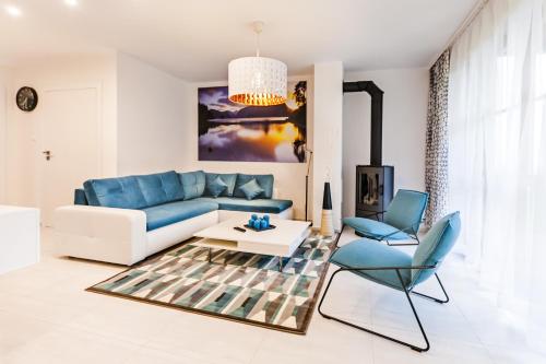 ein Wohnzimmer mit einem blauen Sofa, einem Tisch und Stühlen in der Unterkunft Apartamenty Sun & Snow Komuny Paryskiej in Karpacz
