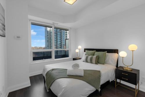 Un dormitorio blanco con una cama grande y una ventana en Luxury 2BR - Subway/Pool/Gym/Sauna + Free Parking, en Toronto