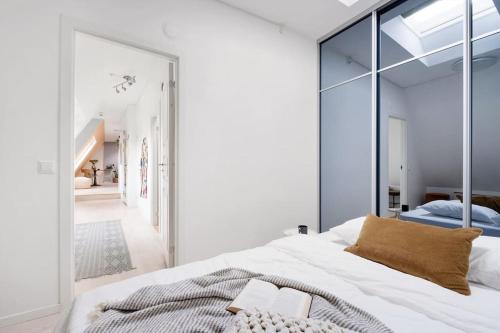1 dormitorio con 1 cama blanca grande y espejo grande en Loft in the middle of Oslo City Center -2 bedrooms, en Oslo