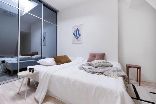 1 dormitorio con 1 cama blanca grande y espejo en Loft in the middle of Oslo City Center -2 bedrooms, en Oslo