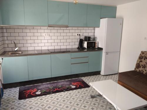 a kitchen with blue cabinets and a white refrigerator at A Travesía Dos Soños, Pedreiras in Sarria