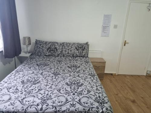 un letto con piumone bianco e nero in una camera da letto di Private Rooms in London, a Londra
