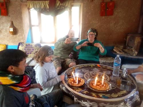 a group of people sitting around a table with lit candles at Auberge Tafouyt in Tamtetoucht