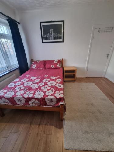 sypialnia z łóżkiem z czerwoną kołdrą w obiekcie Private Rooms in London, w Londynie