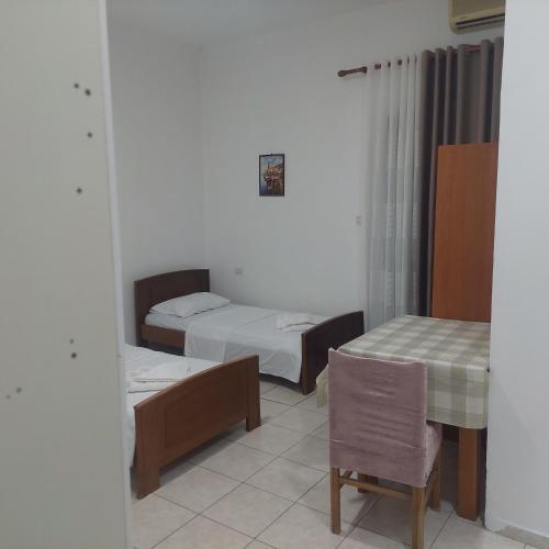 a room with two beds and a table and a chair at Hostel Casa Mia SR in Sarandë