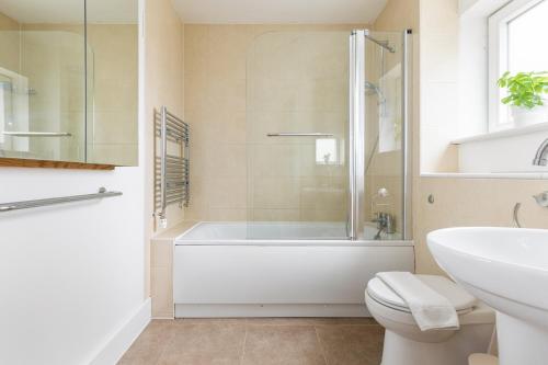 a bathroom with a tub and a toilet and a sink at Modern 2 Bed Apartment London Lewisham - Perfect for Long Stays in London