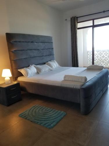 a bedroom with a large bed with a large window at Almasi beach house in Mtwapa
