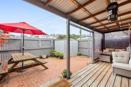 a patio with a picnic table and an umbrella at MOANA I Walk to Beach & River in Ocean Grove