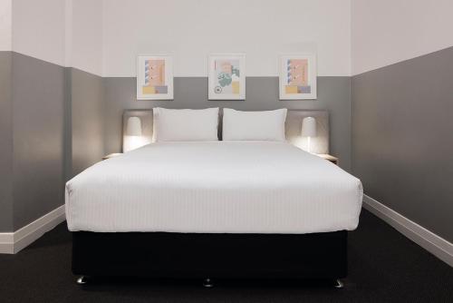 a bedroom with a large white bed with three pictures on the wall at The Ultimo in Sydney