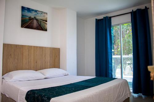 a bedroom with a bed with blue curtains and a window at Hotel Grand Horizon Rodadero in Santa Marta