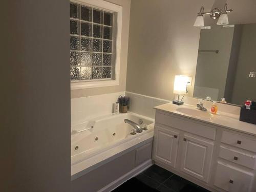 a bathroom with a tub and two sinks and a mirror at Beautiful Home located in an Amazing Neighborhood! in Winterville