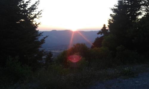 a sun setting on a hill with trees and bushes at Archontiko Nikolopoulou in Vytina