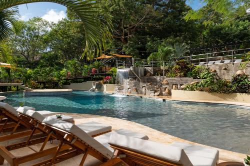 a swimming pool with chairs and a waterfall at TreeCasa Hotel & Resort Nicaragua in San Juan del Sur