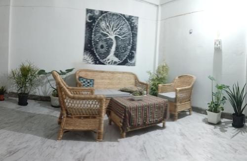 Habitación con sillas de mimbre, mesa y una foto en Serendipia, en Dimāpur