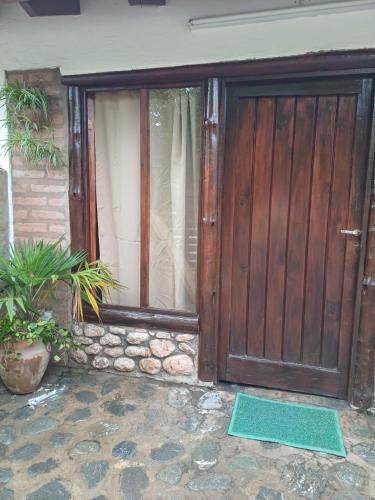 eine Holztür eines Hauses mit Pflanzen davor in der Unterkunft Departamento Juana Azurduy in Merlo
