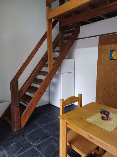eine Holztreppe in einem Zimmer mit einem Tisch in der Unterkunft Departamento Juana Azurduy in Merlo
