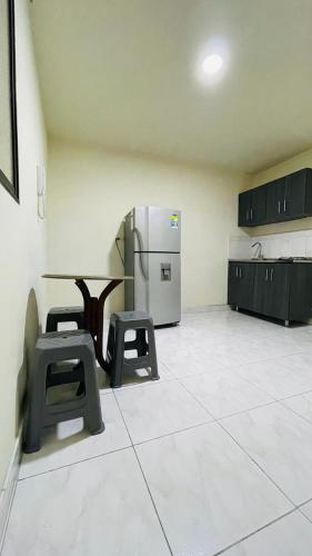 a kitchen with a table and two stools and a refrigerator at Aparta-estudio amoblado en Medellin, Campo Valdes in Medellín
