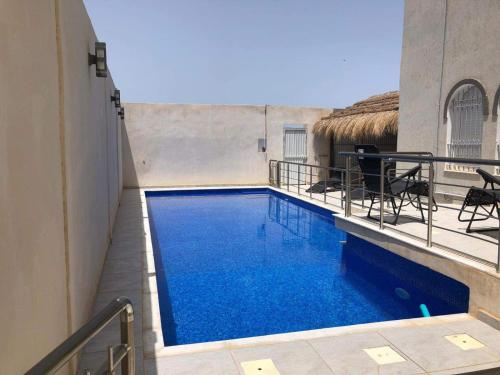 a swimming pool with blue water in a building at La villa H in Houmt Souk