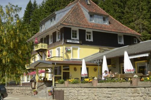 a yellow building with white umbrellas in front of it at Gasthaus Hotel Löffelschmiede in Hinterzarten