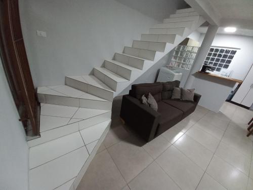 uma sala de estar com um sofá e escadas em Casa de Praia - Frente para o MAR em Xangri-lá