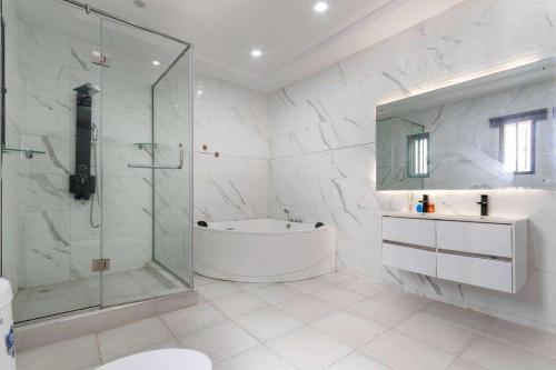 y baño blanco con bañera y ducha. en Luxurious Six Bedroom Apartment, en Lekki