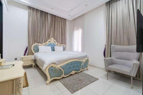 ein Schlafzimmer mit einem großen Bett und einem Stuhl in der Unterkunft Luxurious Six Bedroom Apartment in Lekki