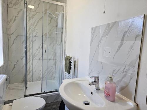 a white bathroom with a sink and a shower at Modern & Stylish 1 bedroom flat in Bridgend town in Bridgend
