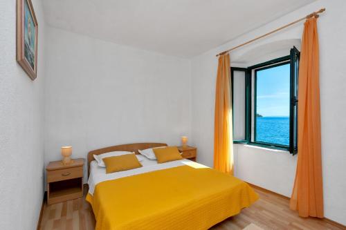 a bedroom with a yellow bed and a window at Apartments by the sea Igrane, Makarska - 20373 in Igrane