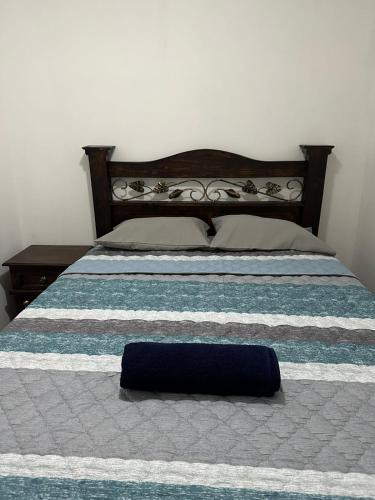 a bed with a blue and white striped bedspread and a blue pillow at NEIZAN HOTEL in Antigua Guatemala