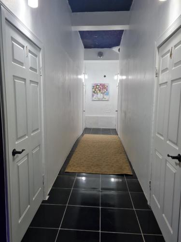 a hallway with two doors and a tile floor at Sky Beach Rooms in Lucea