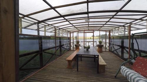 a greenhouse with a table and benches on a deck at Sodyba Brazylija in Taraldžiai