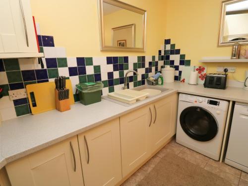 a kitchen with a sink and a washing machine at Stags Cottage in North Molton