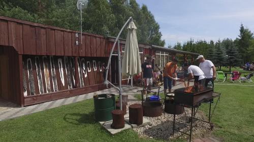 a group of people standing around a grill in a yard at Sodyba Brazylija in Taraldžiai