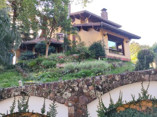 uma casa com uma parede de retenção e um jardim em Pousada Oscar Magic Gramado em Gramado